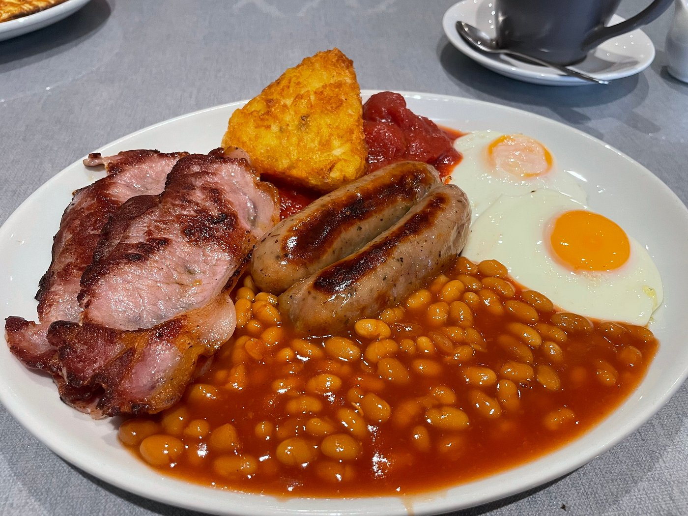 A proper fry-up plate with bacon, eggs, sausages, beans, hash brown and tea